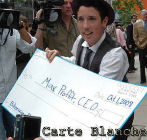 Man at a protest, holding a blank check made out to “Max Proffit, CEO, for Billionaire Bailout.”