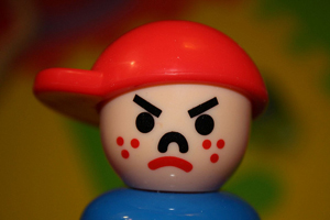 A photograph of an older fisher-price little people figure that is a bully. He is a mean looking boy with a baseball hat on.