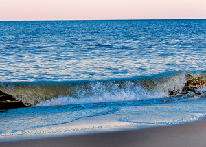 A photograph of a small wave as it approaches the beach