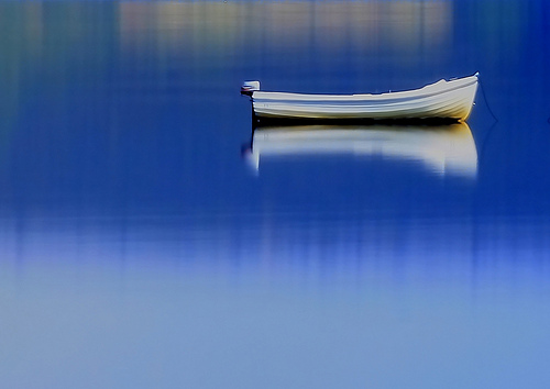A photograph of a boat on very still blue water