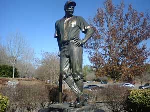 A marble statue of Casey, leaning on a baseball bat while standing with legs crossed and one hand on hip.
