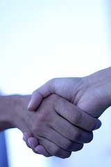 A photograph of two hands grasping each other in a handshake.