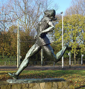 A photograph of a statue of a female athlete running with her head thrown back