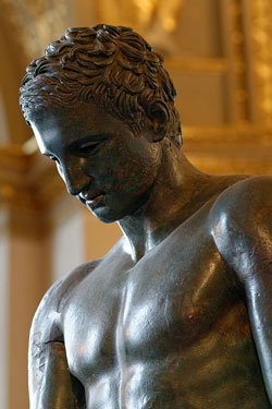 A photograph of an ancient Greek statute of a sad looking athletic man