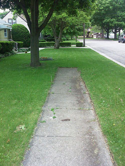 A photograph of a sidewalk that comes to an end in a grassy yard