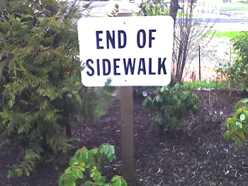 A photograph of a sign in a park that reads “End of the Sidewalk”