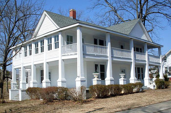 A photograph of a two story house with a wraparound porch