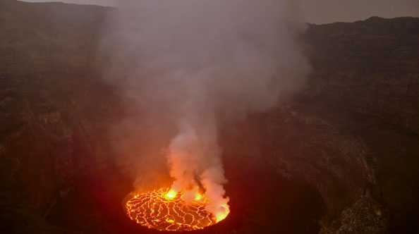 A photograph of a volcano cone with active lava and smoke