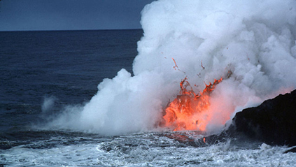 A photograph of molten lava flowing from the land into the sea