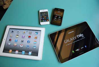 A photograph of several devices on a table. They are smart phones and tablets.