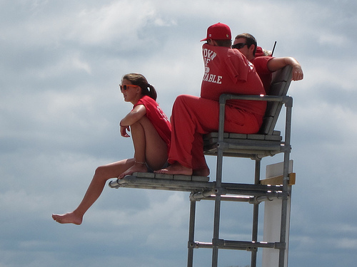 A photograph of three teenaged lifeguards on a lifeguard stand.