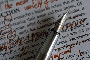 A close-up picture of an elegant fountain pen. The page underneath the pen is an essay on physical fitness, covered with revisions in a dark red ink.