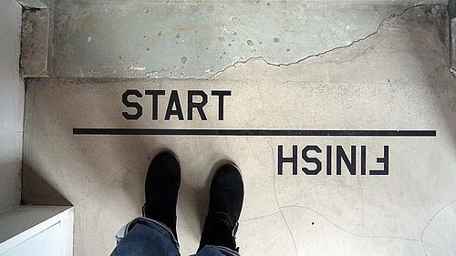 a photo with the camera pointing downward at the photographer’s feet. The photographer is standing at a line that reads “Start” on one side and “Finish” on the other, about to walk over the word “start.