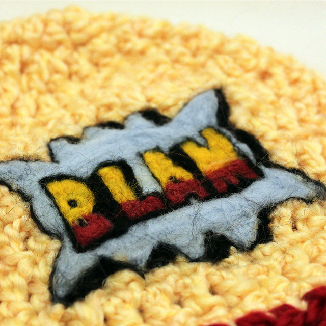 A patch on coarse fabric bearing the word “BLAM”