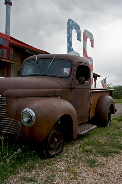 An old, rusted truck in front of a building