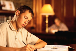 Image of student writing and studying in the library.