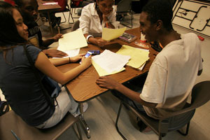 A photograph of a three students, two females and a male, working together at a table in a classroomi