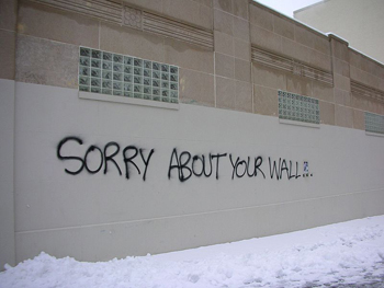 This photo displays an example of paradox: graffiti on a wall that reads “Sorry about your wall.”