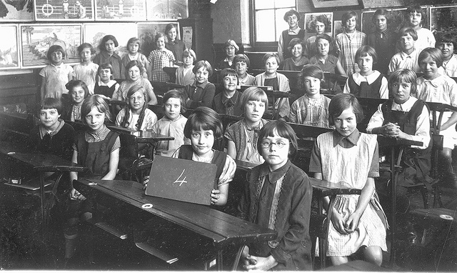 Black and white photo of school girls seated at desks in the 1930s