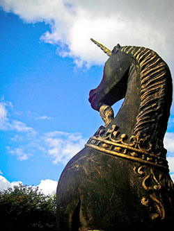 A photograph of a statue of a unicorn silhouetted against the sky.