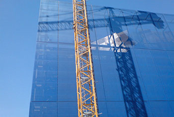 A photograph of a crane next to a building that is under construction.