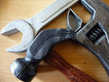 A photograph of some tools, a hammer, a crescent wrench, and a box wrench.