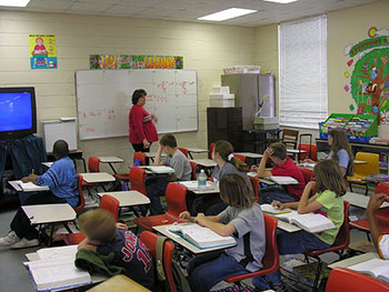 A photograph of a female teacher teaching in front of a class.