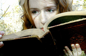 A photograph of a girl reading an old book. She has a look of concern on her face.