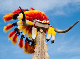 A photograph of an American Indian war bonnet made of eagle feathers and colored beads.