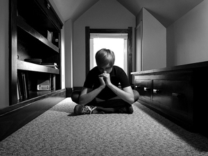 = A photograph of a boy sitting in a room alone.