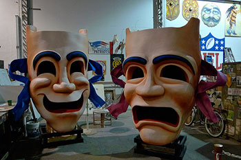 A photograph of two large drama masks, one happy, one sad.