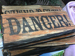 Photo of a wooden sign that reads, “Danger!”