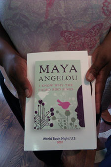 A photograph of a woman holding a copy of the book “I Know Why the Caged Bird Sings” by Maya Angelou.