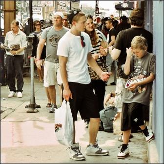 A photograph of a much bigger boy acting in a threatening manner to a smaller boy on a crowded sidewalk