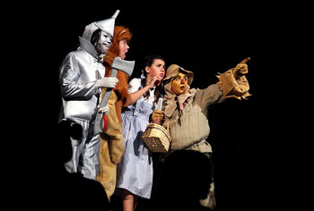 A photograph of a school production of The Wizard of Oz. Shown are the Tin Man, the Cowardly Lion, Dorothy, and the Scarecrow.