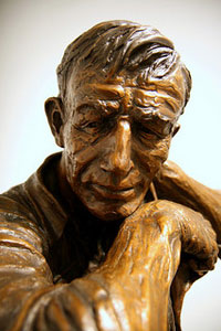 A photograph of a carved wood sculpture of a man in his 30s or 40s
