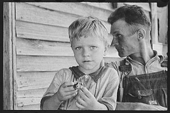 A photograph of a father and a son sitting on the porch of their home. The picture is form the 1930s.