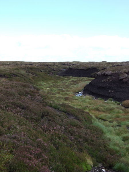 A photograph of a Scottish moor. This one has a dry, grass covered creek bed running through it.
