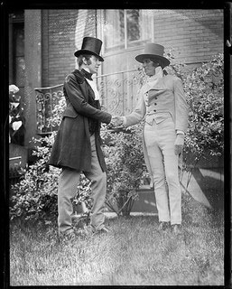A pair of statues, men shaking hands dressed in 19th century formal clothes