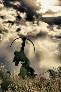 A photograph of a statue of a Native American hunter shooting an arrow at the sky