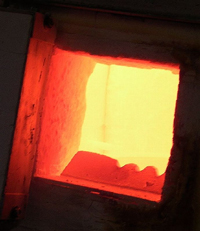 A photograph of a an open furnace showing the blazing fire inside