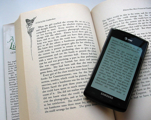 A photograph of an open book with a smart phone reader on top of it