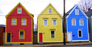 A photograph of three identically built houses that are painted different primary colors