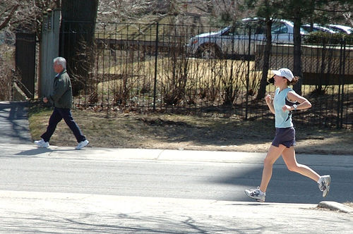A photograph of a man walking and a woman running along a trail