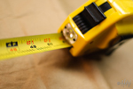 A photograph of a tape measure extended over a piece of wood