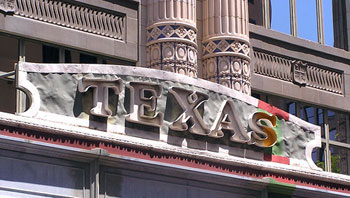 A carved sign outside of a business that reads “TEXAS.” All of the letters are capitalized.