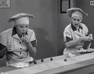 Lucy and Ethel wrapping and eating chocolates in the chocolate factory job episode of I Love Lucy