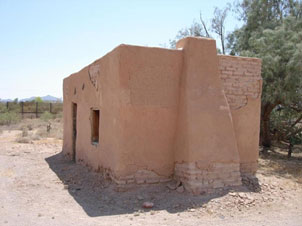 adobe house with rectangular front face, a rectangular door, and a square window