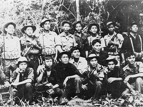 A photograph of Vietnamese guerilla fighters posing as a group. They are holding rifles and other combat equipment.