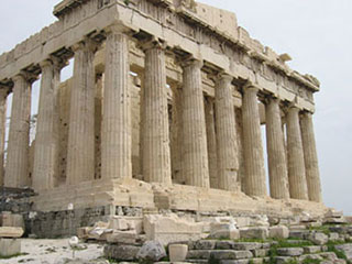 A photograph of the Greek Parthenon in Athens. It is a classical Greek structure in that it has large columns supporting a roof. In this structure the roof has collapsed over time and all that remains is the foundation, the columns, and portions of the roof's perimeter.